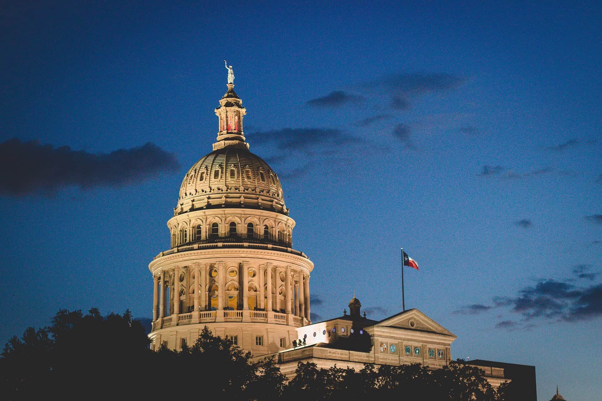 The Texas State Capitol dome lit gold at dusk.
