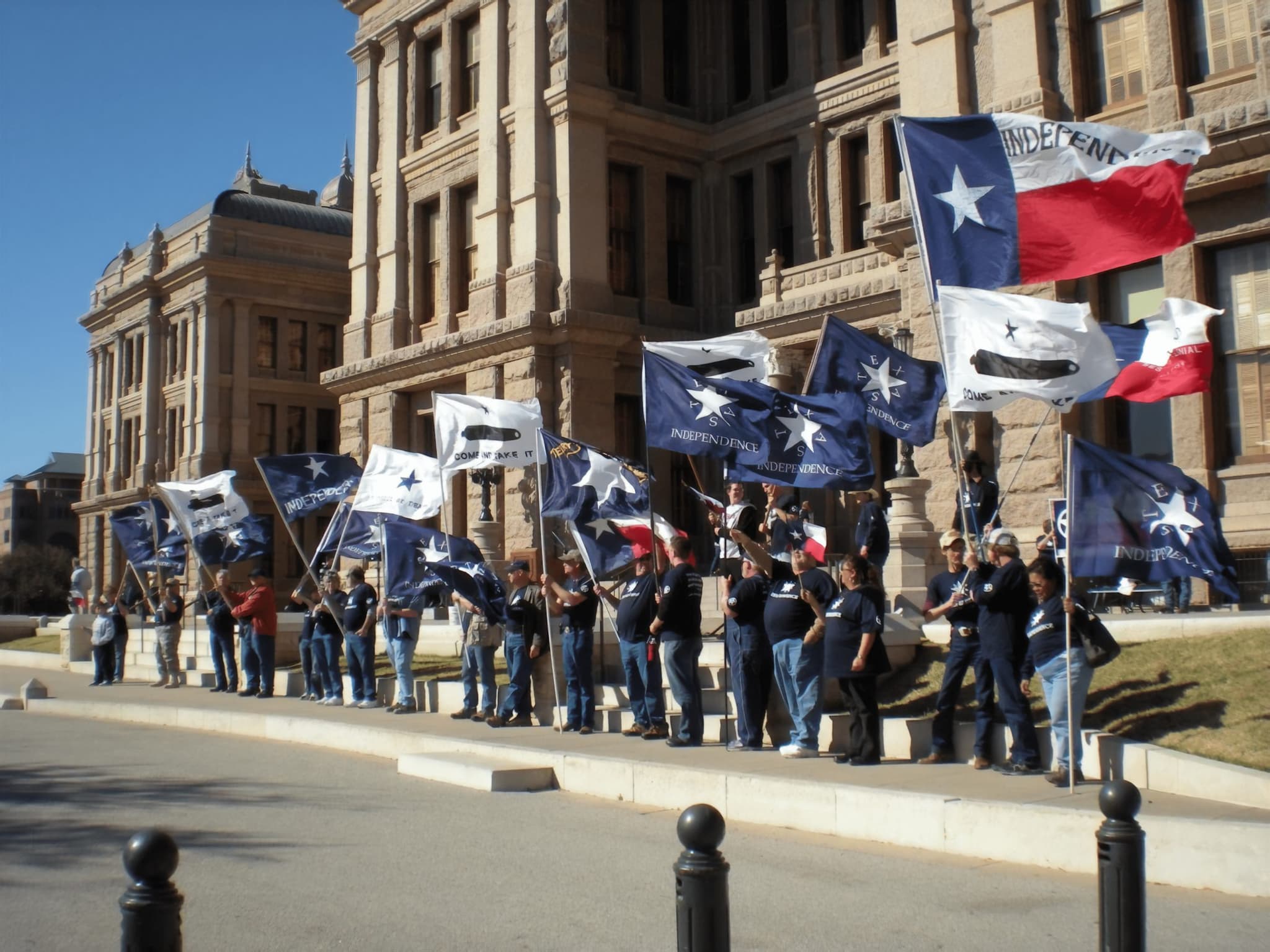 Texans rallying at the Texas State Capitol with Texas independence flags.